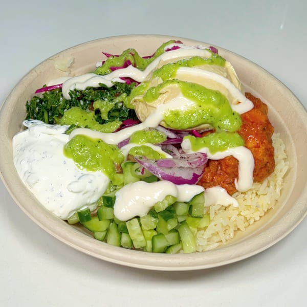 A vibrant Nana Street Food bowl with rice, chicken, hummus, tabbouleh, cucumbers, and sauces.